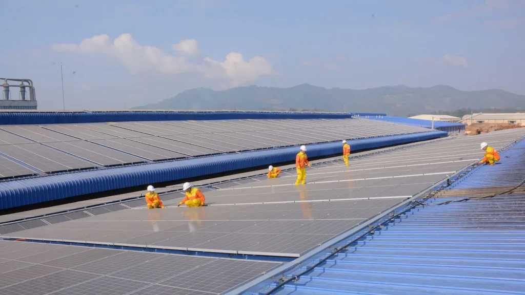 Instaladores colocando paneles solares en el techo de una nave industrial
