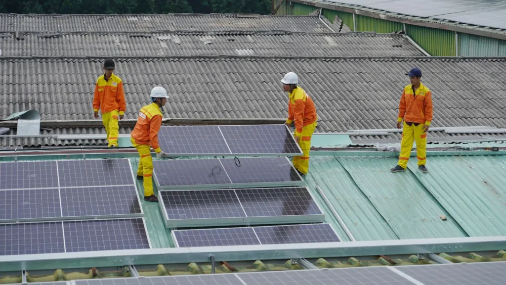 Cuadrilla revisando paneles solares en el techo de una nave industrial