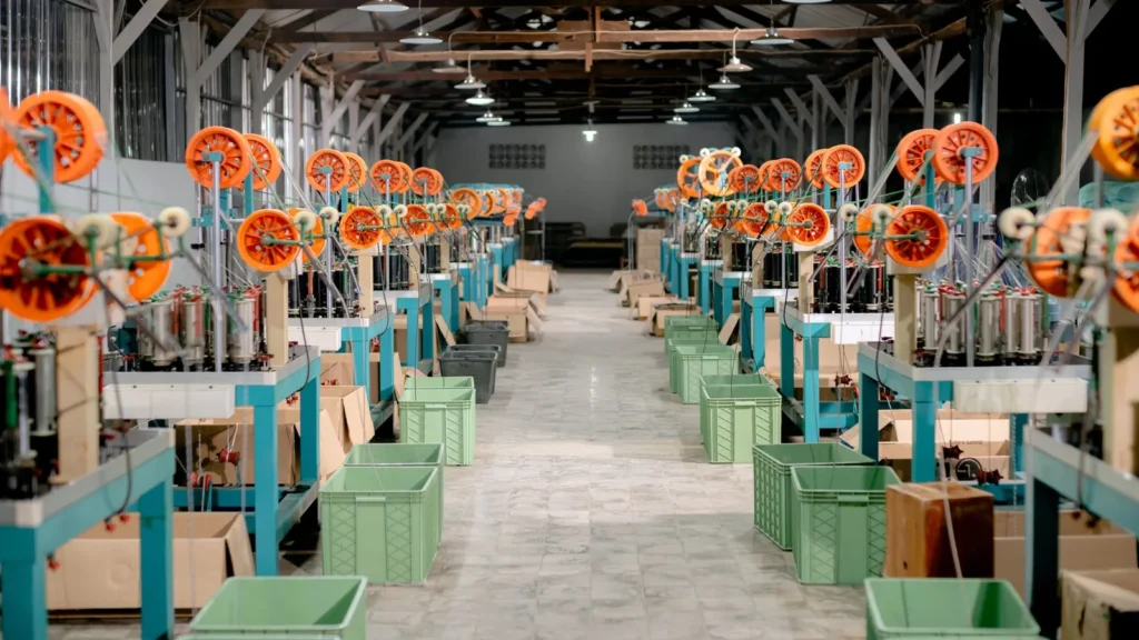 Nave industrial con hileras de máquinas bobinadoras de hilo