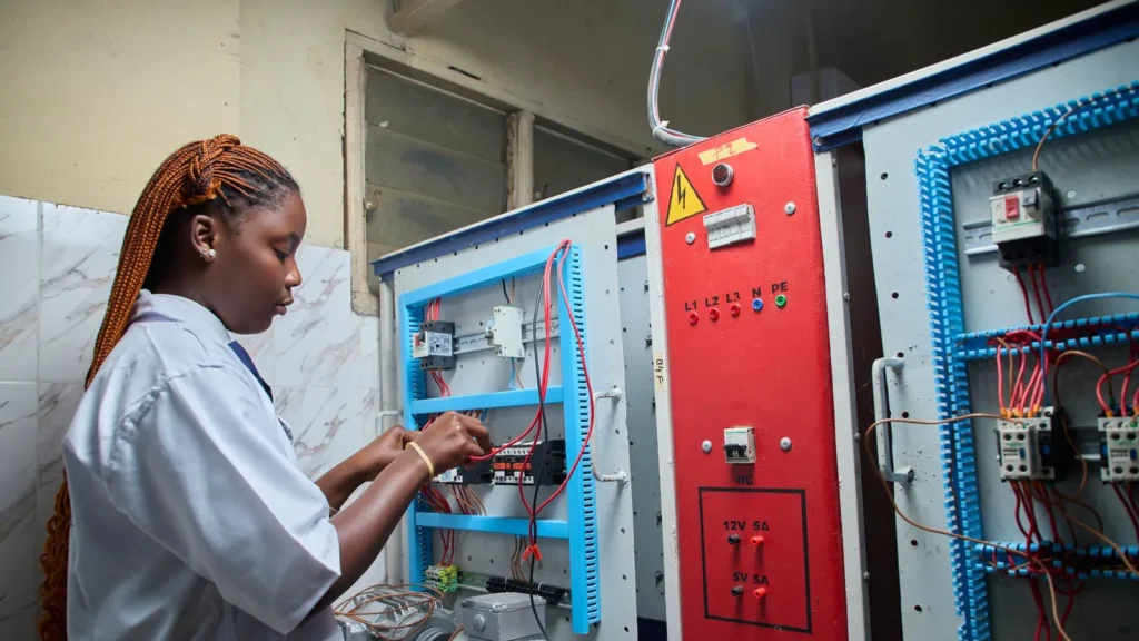 Técnica revisando un tablero de control eléctrico en planta