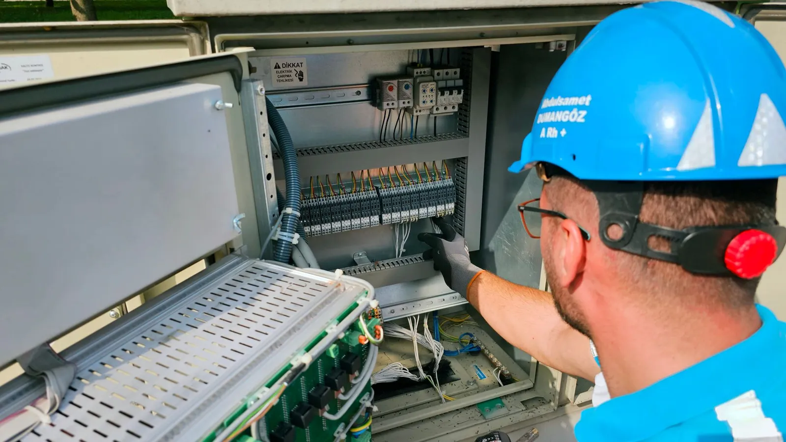 Técnico con casco revisando el cableado de un gabinete de control industrial