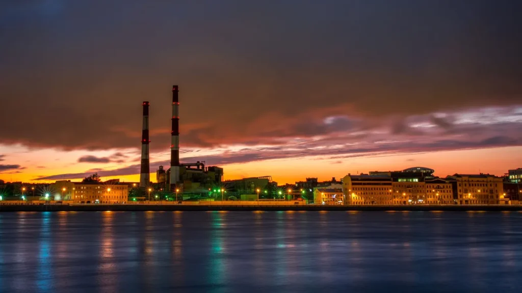 Chimeneas industriales al atardecer, reflejadas en el agua