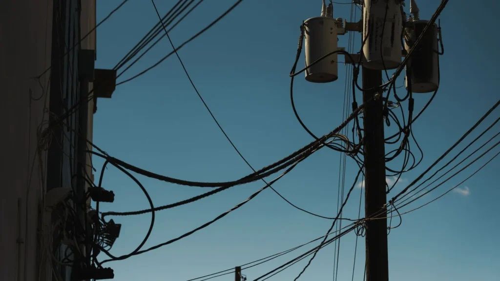 Líneas eléctricas y transformadores en un poste contra el cielo azul