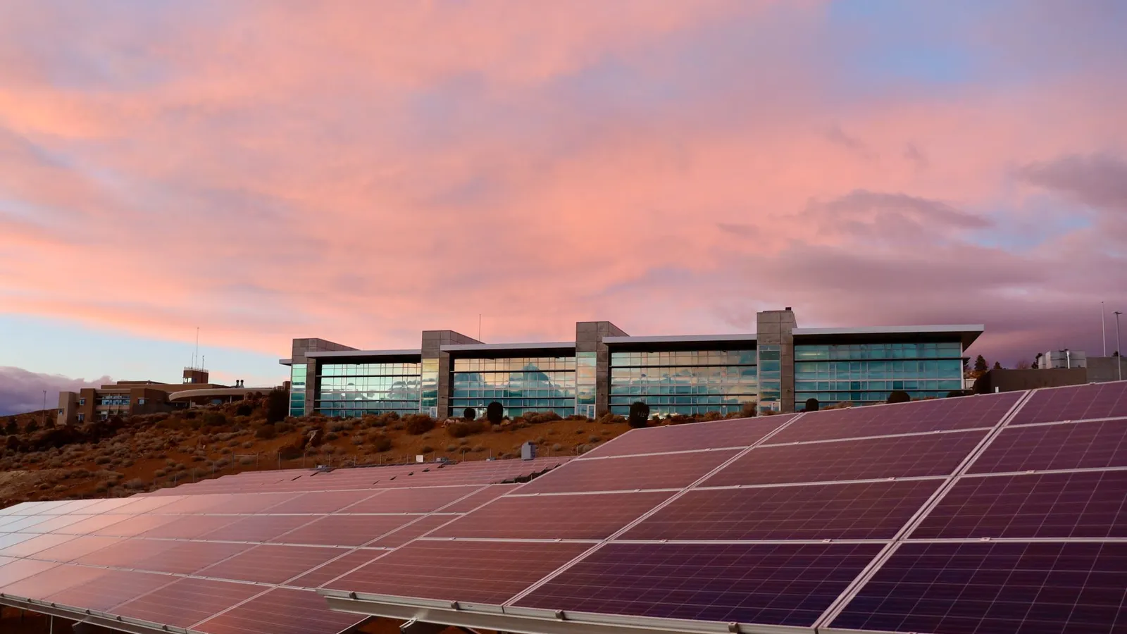 Paneles solares frente a un edificio moderno al atardecer