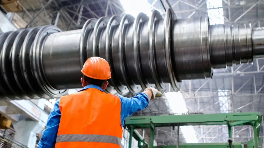 Técnico con casco inspeccionando el rotor de una turbina en una planta