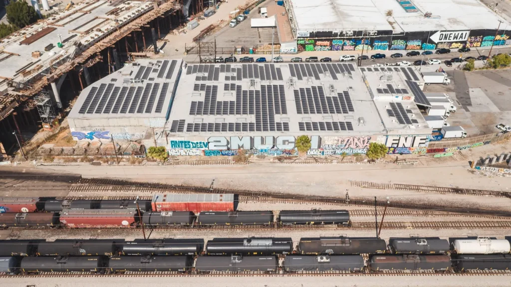 Vista aérea de una nave con paneles solares en el techo junto a vías de tren